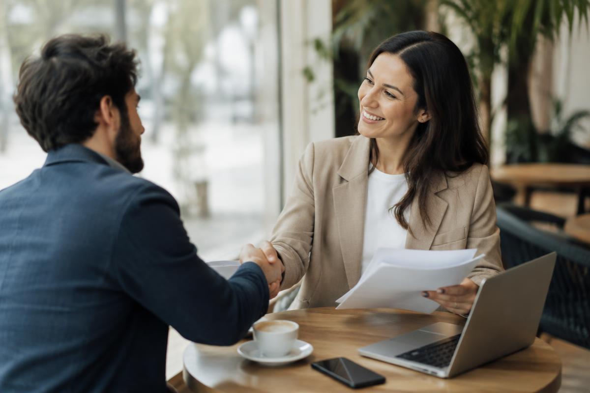 Freelancer handing a printed proposal to a smiling client in a cafe